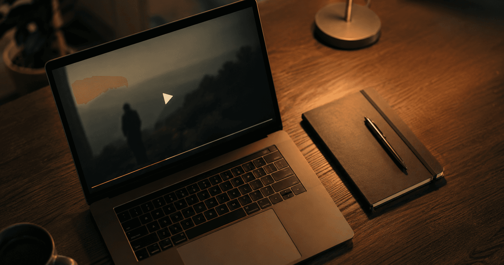  Laptop showing a video course interface on a desk with a notebook